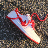 Looped Laces Red Thick Rope Shoelaces tied in a single Air Jordan 1 Low OG White and University Red sneaker laying on its side on cement
