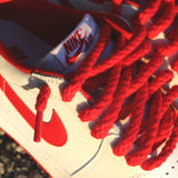 Looped Laces Red Thick Rope Shoelaces tied in a pair of Air Jordan 1 Low OG White and University Red sneakers closeup on cement