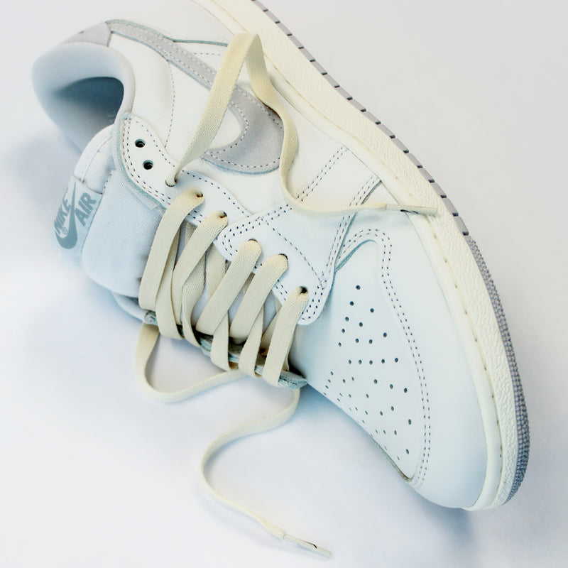 Looped Laces Sail off-white aged cream flat shoelaces in Air Jordan 1 Low Neutral Grey sneaker on white background with close up on laces