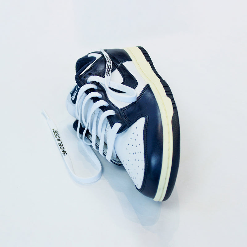 Looped Laces White off-white style shoelaces in quotes in Nike Dunk Vintage Navy sneaker on white background with close up on laces